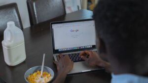 A person browsing Google on a laptop while having cereal breakfast at the table. - A person browsing Google on a laptop while having cereal breakfast at the table., tags: gambling play - pexel