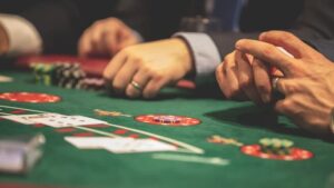 Hands playing blackjack in a casino setting with cards and chips on a green table., tags: brazil - pexel