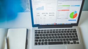 Laptop displaying charts and graphs next to a notebook, ideal for business and tech themes., tags: b2b - pexel