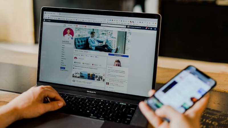 person using both laptop and smartphone - Facebook page of an entrepreneur's social media on desktop and mobile., tags: abandoned $4 retargeting remarketing - unsplash