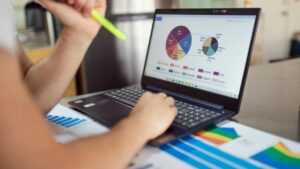 Person analyzing financial charts and graphs on a laptop with colorful documents, showcasing market analysis., tags: casino ads - pexel