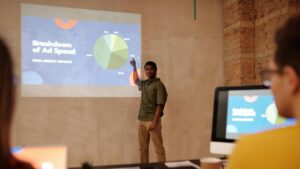 Young man delivering a business presentation on ad spend with charts and graphs in a modern office setting., tags: google ads - pexel