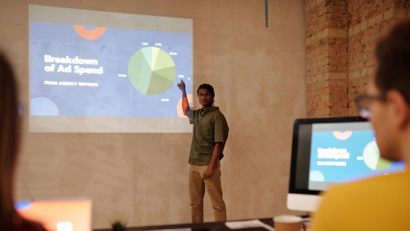Young man delivering a business presentation on ad spend with charts and graphs in a modern office setting., tags: google ads - pexel